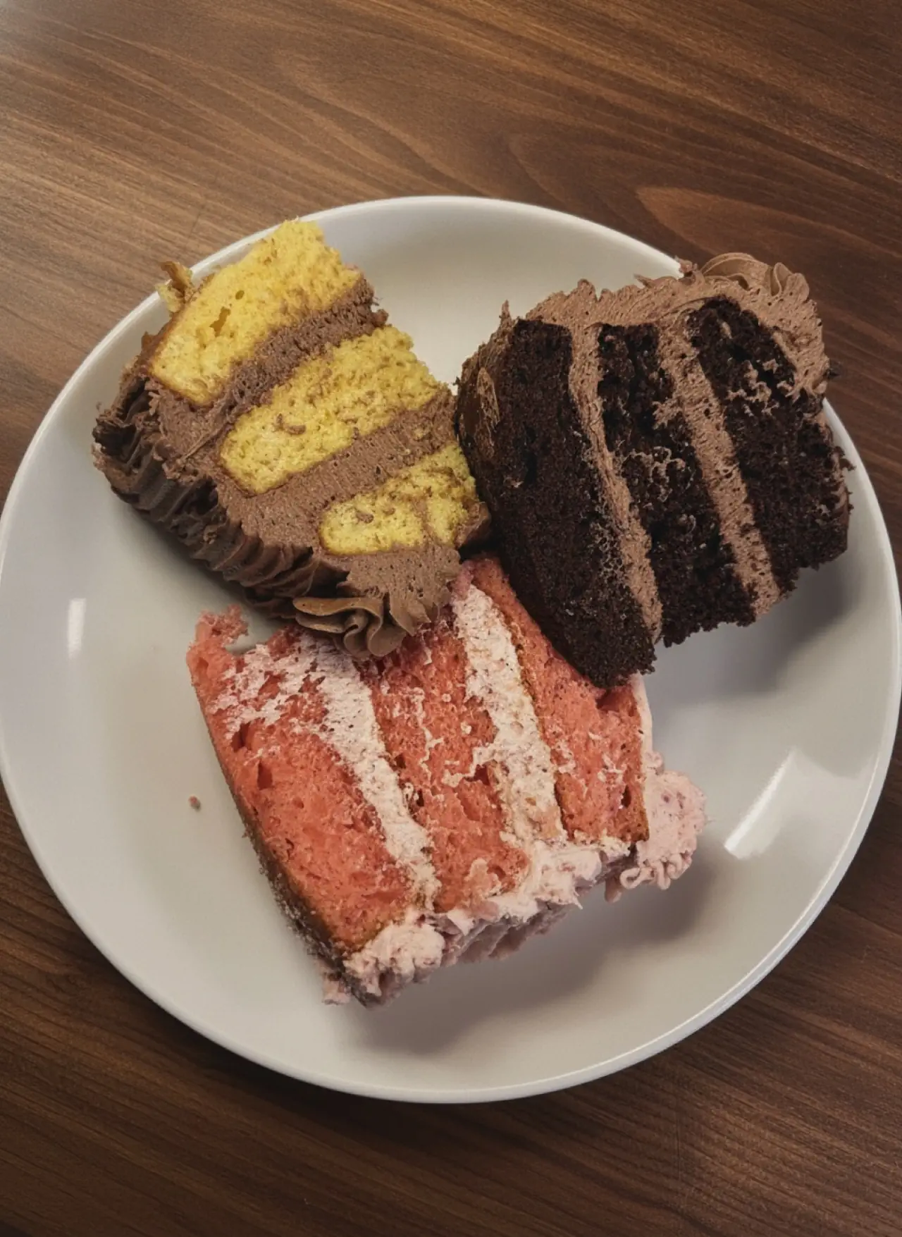 Slices of yellow, chocolate, and strawberry layer cake on a plate