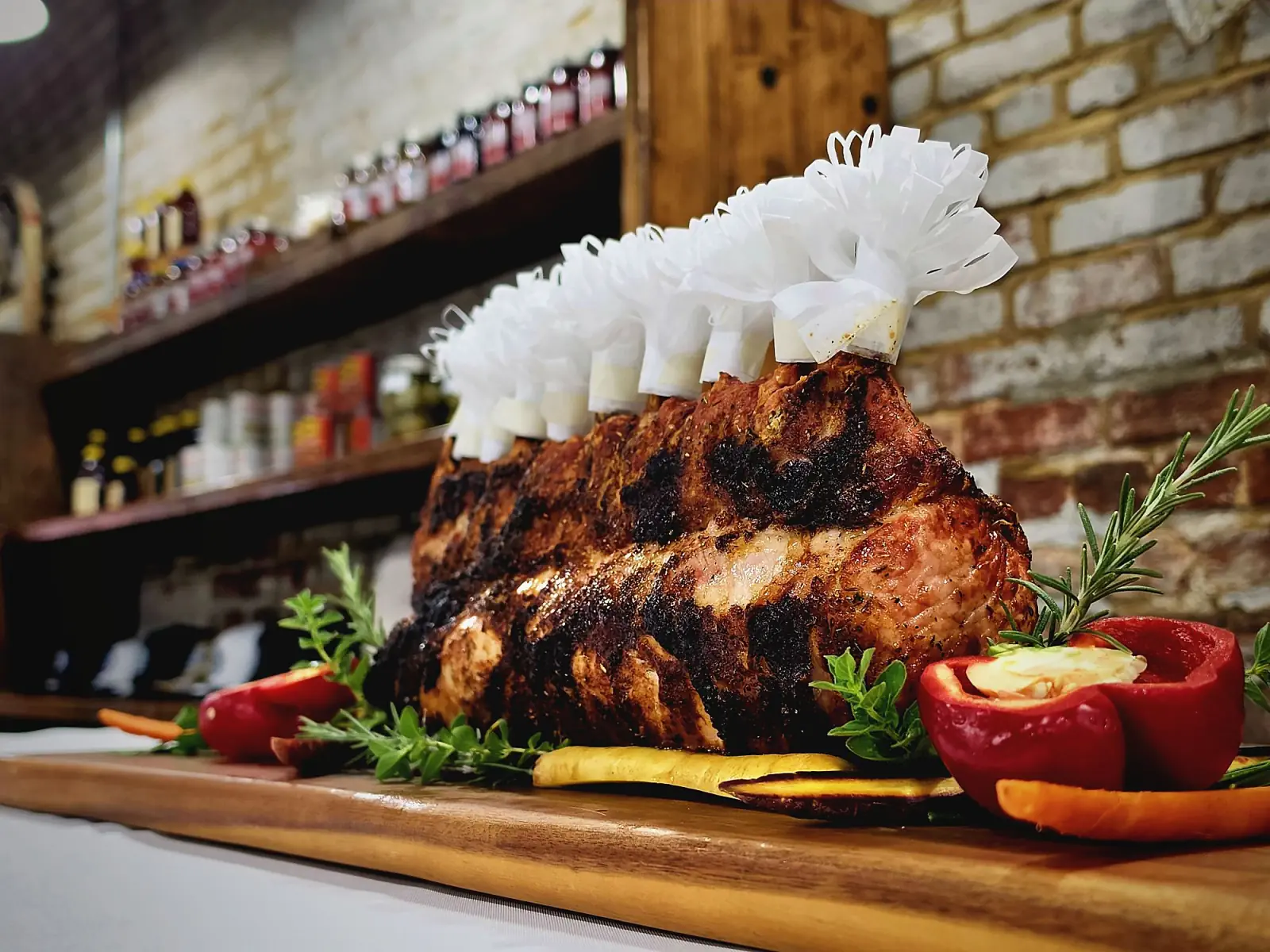 A frilled crown roast on a cutting board in front of the brick wall