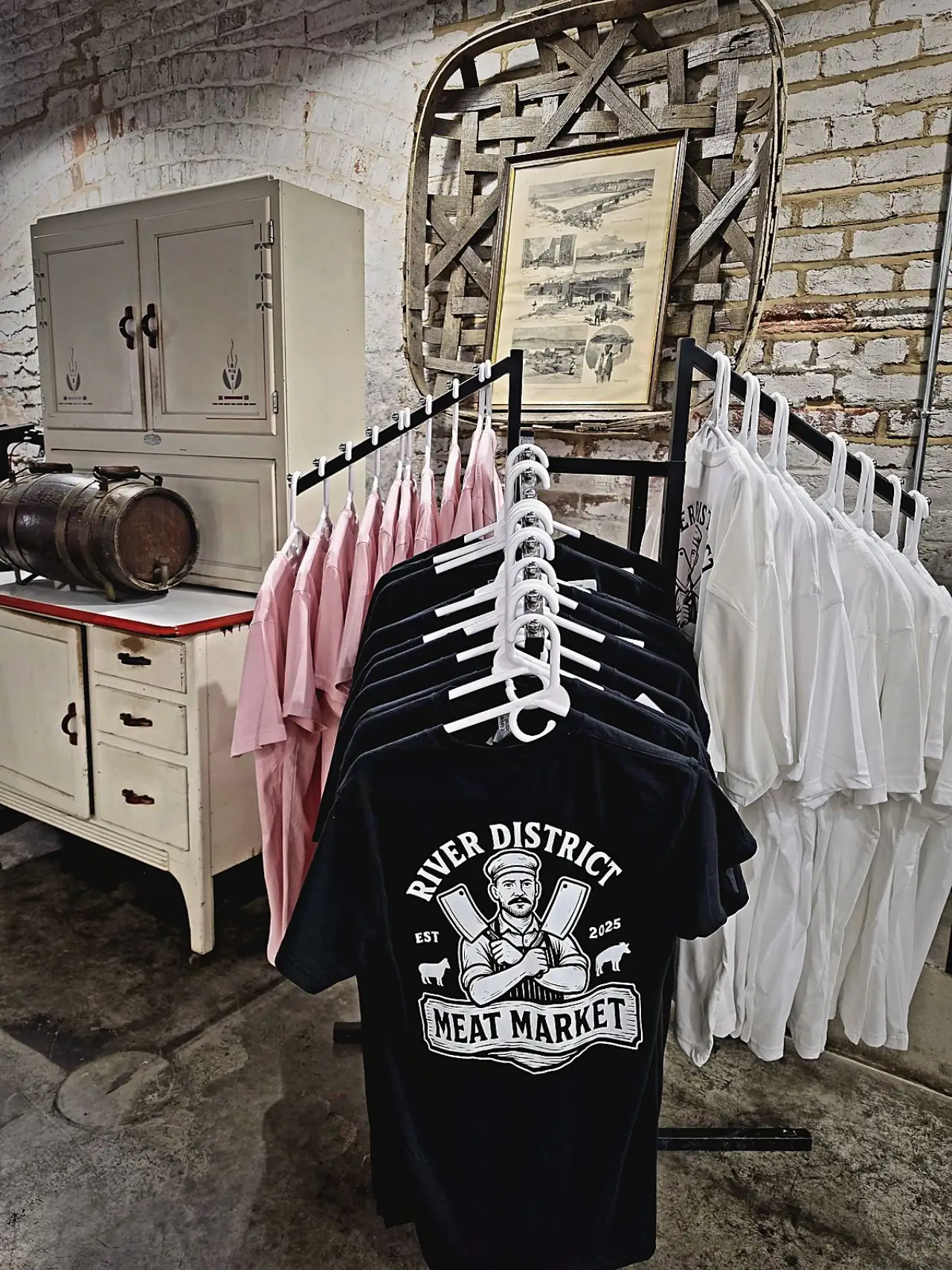 RDMM shirts in pink, black, and white on the merch rack