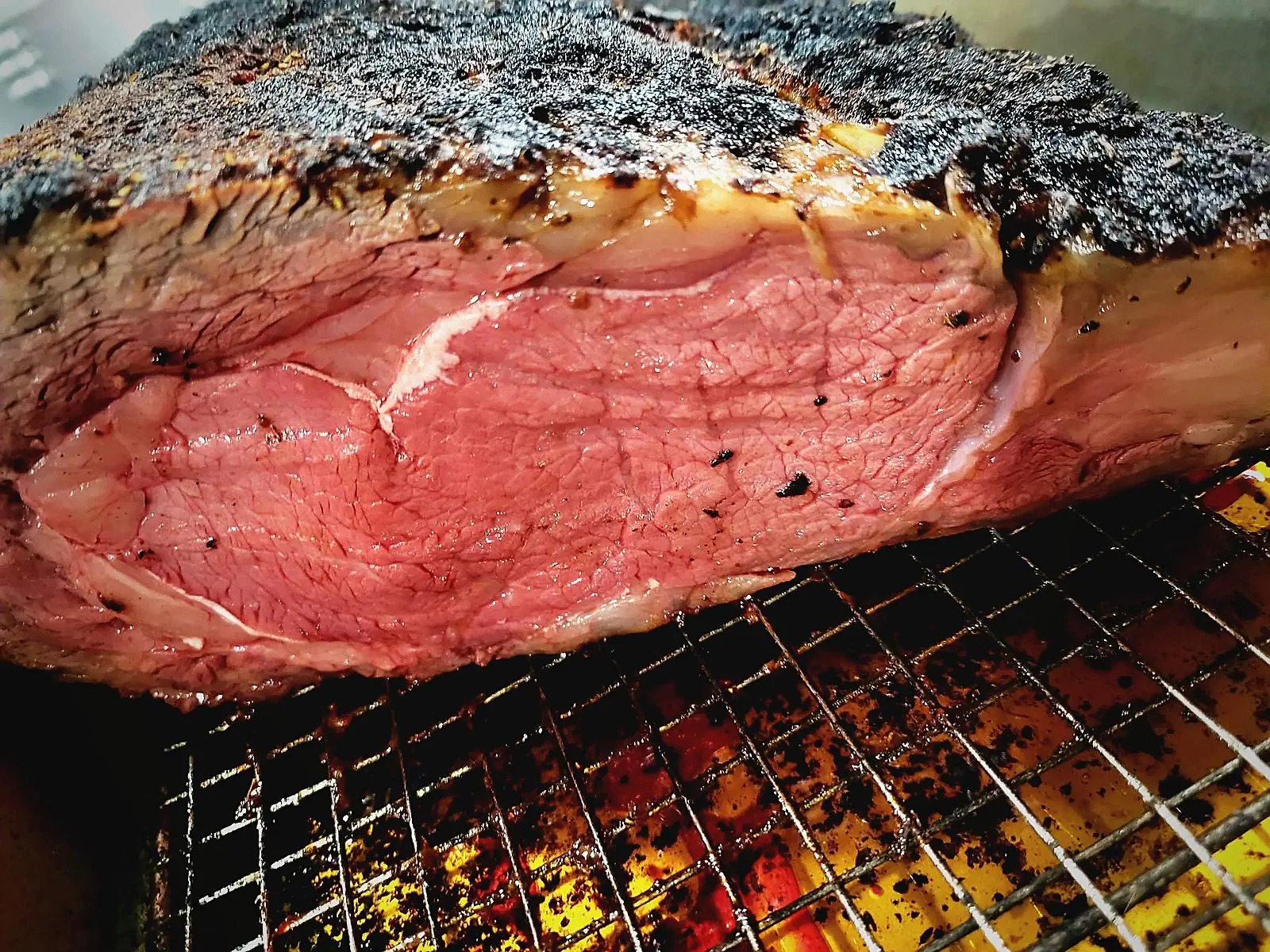 A seasoned roast with a dark crust resting on a rack