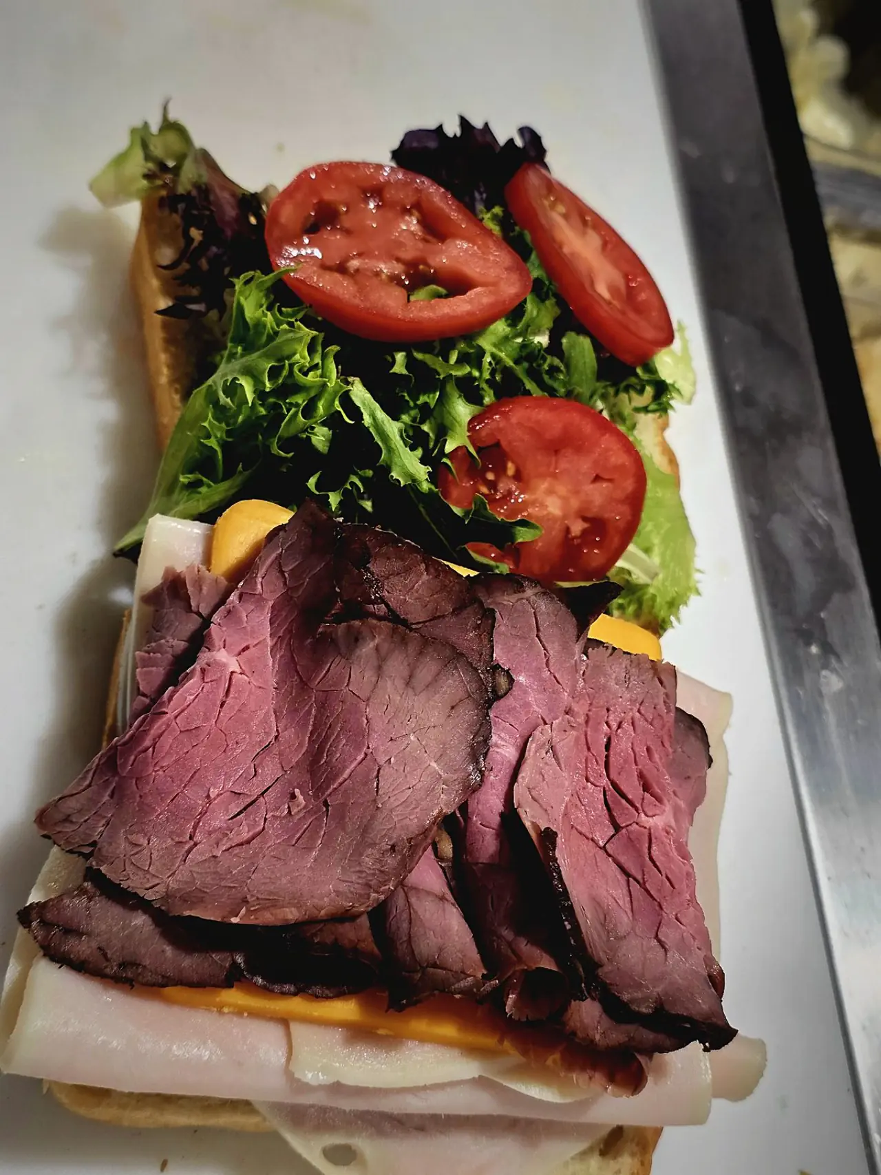 A roast beef sandwich being built at the deli line