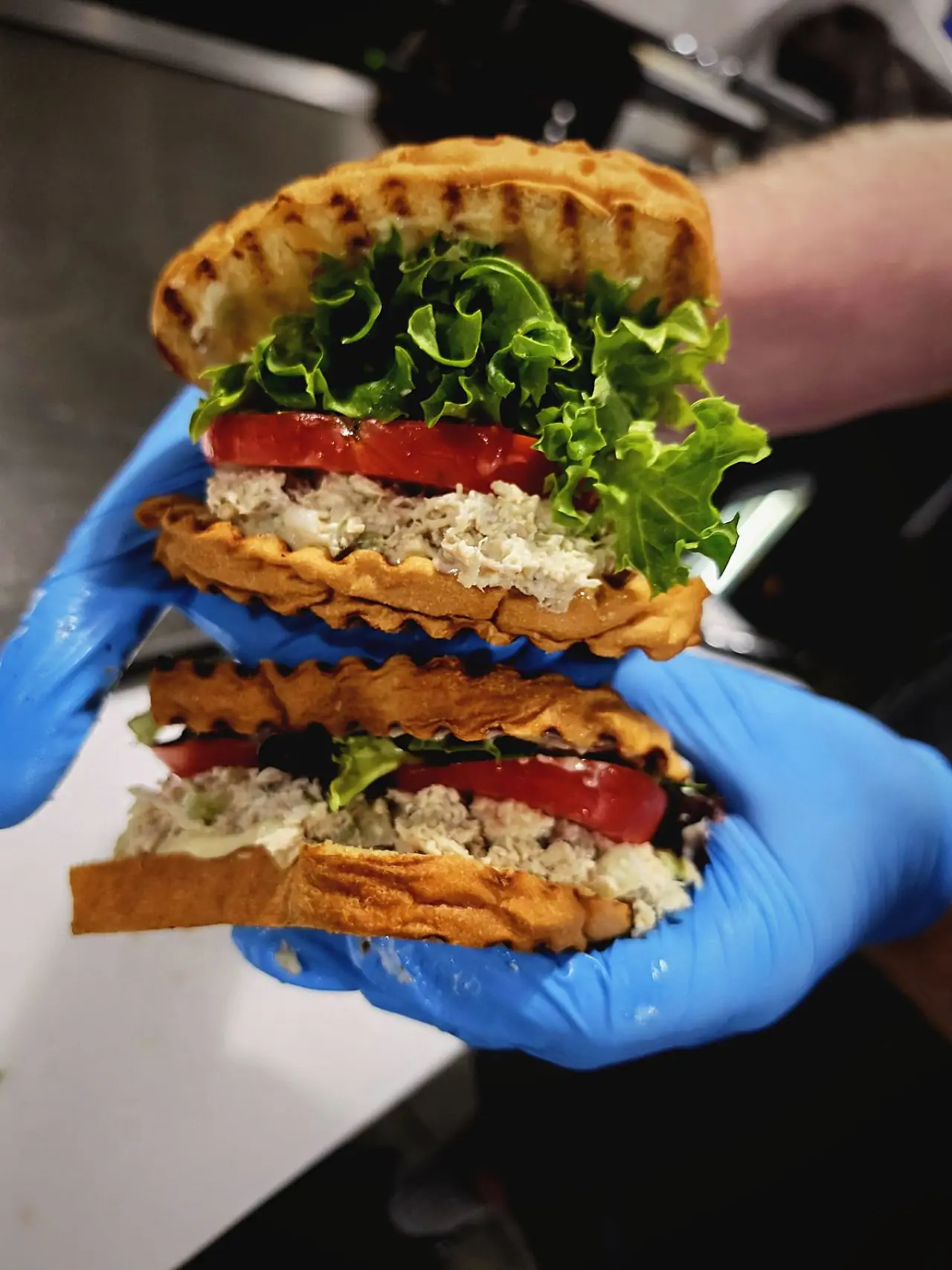 A double-decker chicken salad sandwich held up at the deli line
